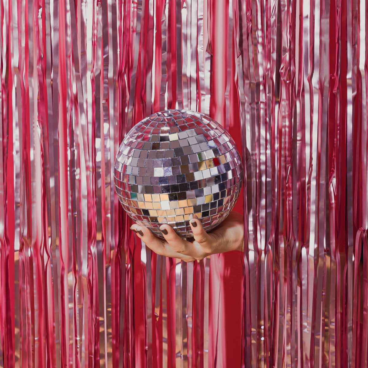 A woman's hand holding a disco ball through party streamers