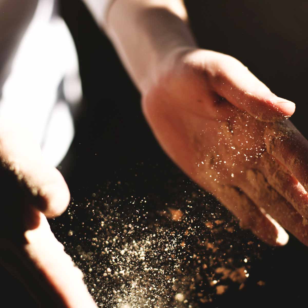 Close-up shot of chef's hands covered in flour making a pizza