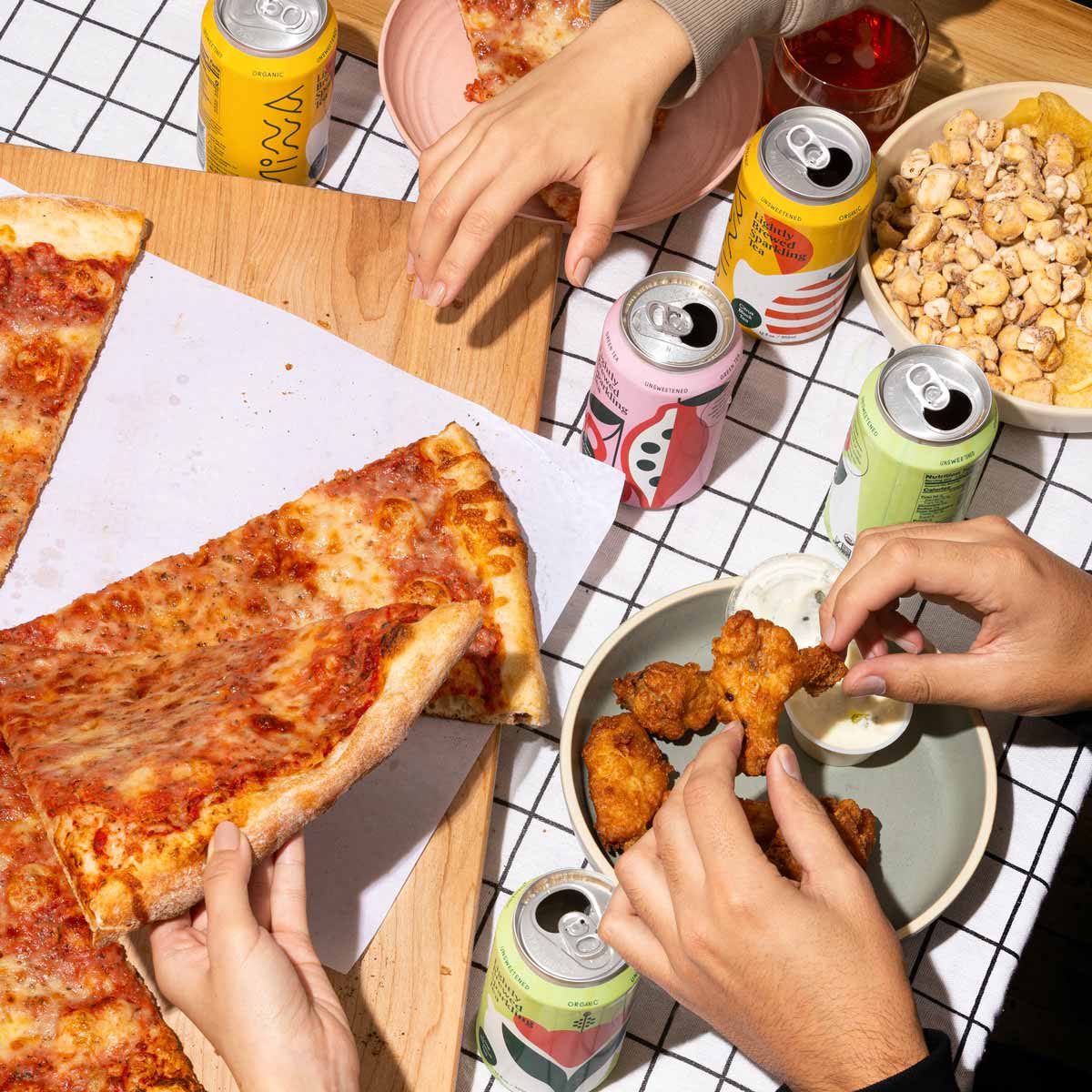 Hands reaching for pizza and wings